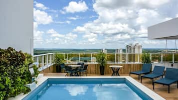 Área de piscina no terraço com vista desobstruída da linha do horizonte da cidade, espaço para sentar ao ar livre e um deck de madeira.