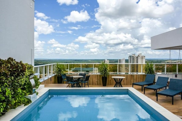 Área de piscina no terraço com vista desobstruída da linha do horizonte da cidade, espaço para sentar ao ar livre e um deck de madeira.