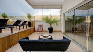 Een modern buitenverblijf met loungestoelen, een bank, een kamerplant en een schommelstoel.