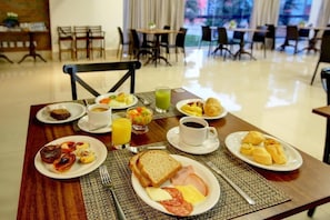 Un desayuno con platos de comida, una taza de café y un vaso de jugo sobre una mesa.