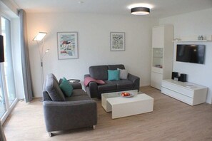 A modern living room with two sofas, a coffee table, a flat-screen TV, and artwork on the walls. - Sonnengarten 17 in Kellenhusen (Kellenhusen)