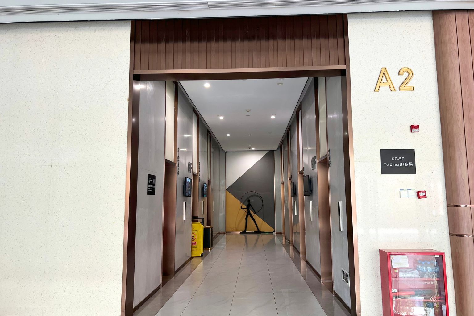A hotel corridor with a sign indicating room A2, a fire alarm, and a vending machine.