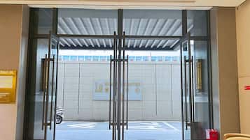 A hotel entrance with a glass door, a sign indicating the hotel name, and a wheelchair-accessible ramp.