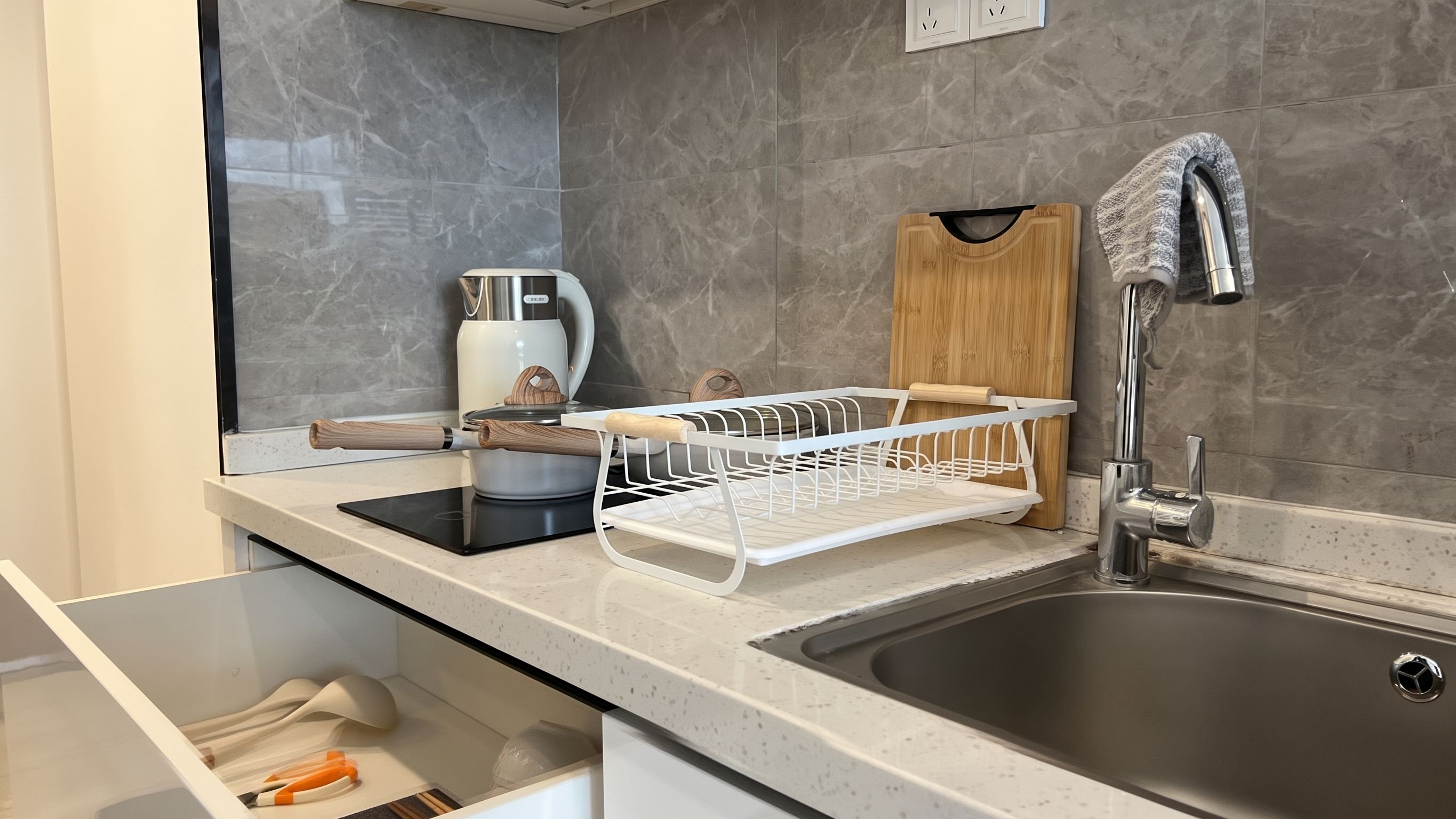 A modern kitchen with a stainless steel sink, a coffee maker, and a dish rack.