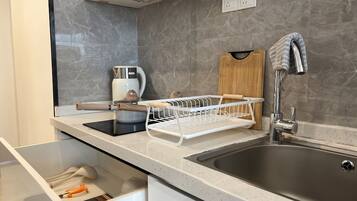 A modern kitchen with a stainless steel sink, a coffee maker, and a dish rack.