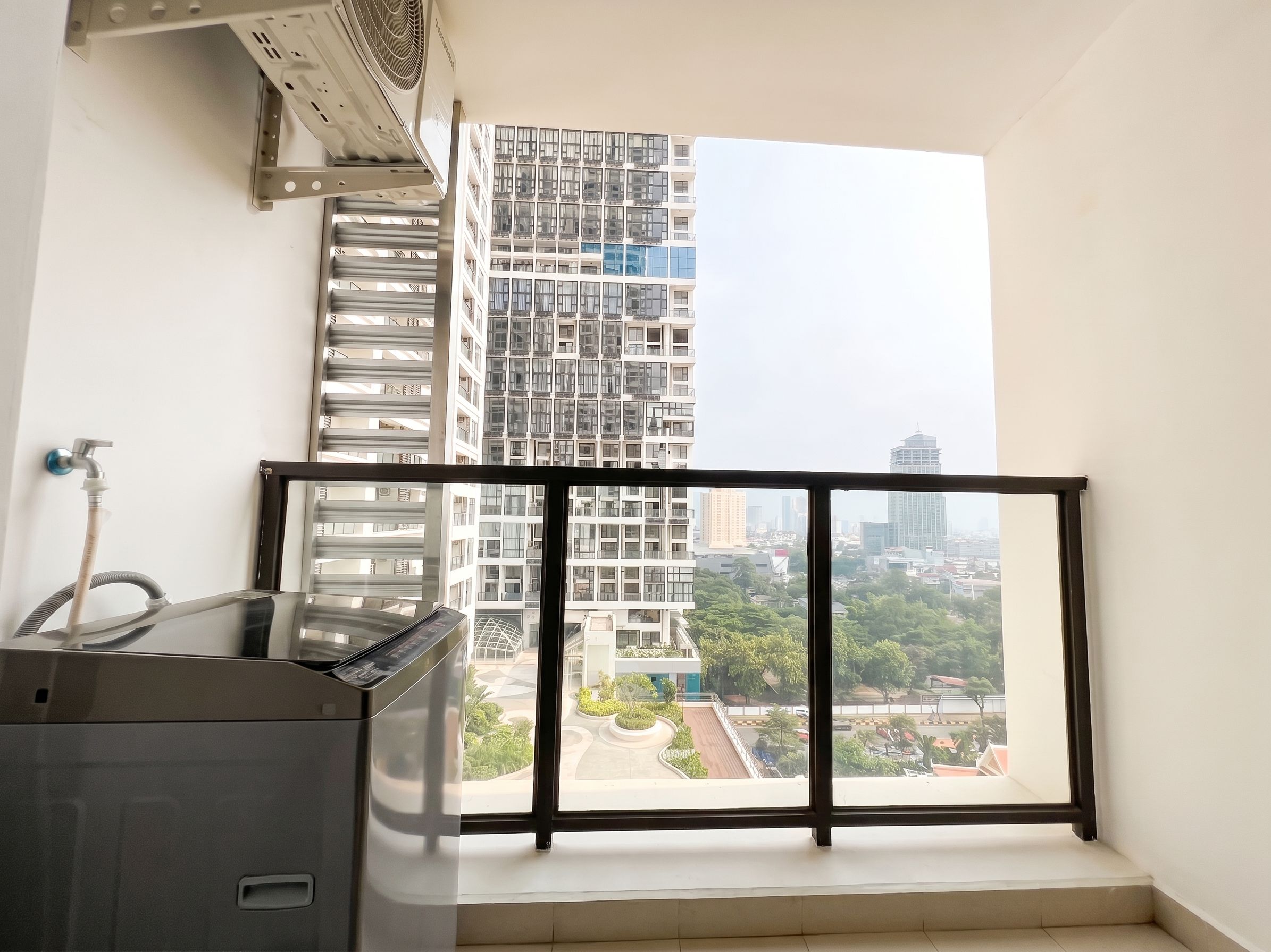A balcony with a view of high-rise buildings, a window sill, and a water heater.