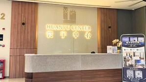 Un comptoir d’accueil avec une enseigne indiquant « HUANYU CENTER » et un panneau d’affichage numérique présentant des annonces immobilières.