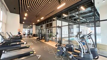 A gym with treadmills, weight machines, and a large window overlooking a pool.