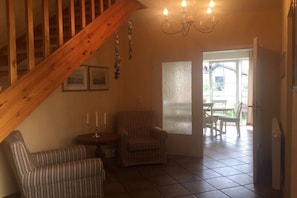 Ein Zimmer mit einer Holztreppe, einem Chandelier, einem Essbereich mit Tisch und Stühlen sowie einem Kühlschrank.