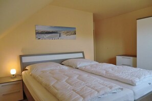 Ein Hotelzimmer mit einem Bett, einem Nachttisch, einer Schublade, einem Beistelltisch und einem Wandbild.