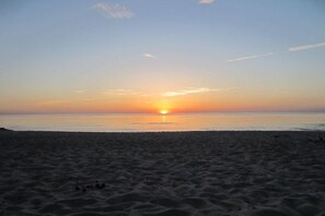 Ein Strand bei einem Sonnenuntergang über dem Wasser.