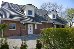 A two-story house with a tiled roof, a brick facade, and a front entrance with a door and windows. - Holiday home in Zingst with swimming pool (Zingst)