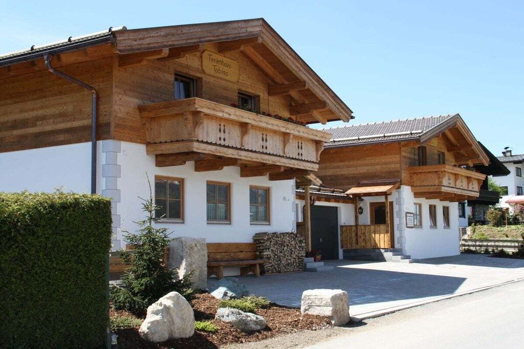 A traditional wooden chalet with a balcony, a wooden bench, and a stack of firewood.