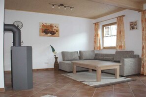 A living room with a sofa set, a coffee table, a fireplace, and a window with curtains. - Holiday home in Going with swimming pool (Going)