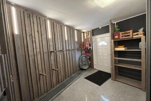 A hallway with a metal vent, a white door, and a wooden shelf unit with storage boxes. - Cabin with 1 bedroom (Maria Alm - Hinterthal)