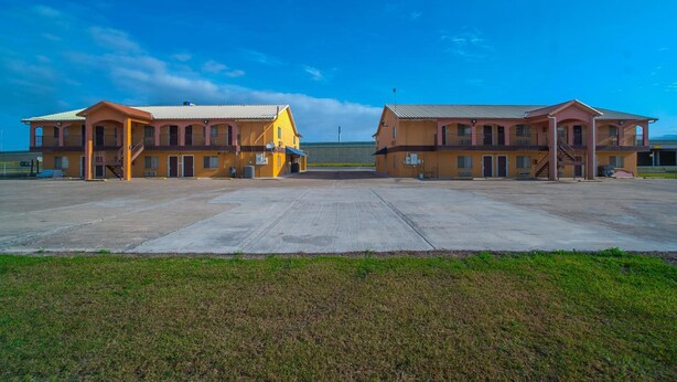 Een tweelaags motel met een centrale binnenplaats, met een plat dak en een eenvoudig, functioneel ontwerp.