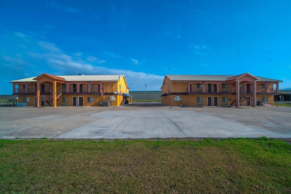 A two-story motel with a central courtyard, featuring a flat roof and a simple, functional design. - Executive Inn And Suites (San Benito)