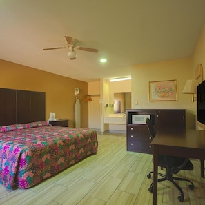 A hotel room with a bed, desk, chair, ceiling fan, and a bathroom visible in the background. - Executive Inn And Suites (San Benito)