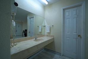 A bathroom with a double sink, a mirror, a towel rack, and a white door. - Executive Inn And Suites (San Benito)