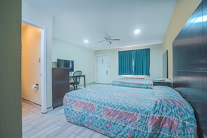 A hotel room with two beds, a desk, a chair, a television, and a ceiling fan. - Executive Inn And Suites (San Benito)