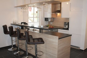 A modern kitchen with a central island, bar stools, and a dining area. - Holiday apartment with 2 bedrooms (Wendisch Rietz)