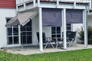 A covered outdoor seating area with tables and chairs, adjacent to a building with large windows. - Holiday apartment with 2 bedrooms (Wendisch Rietz)