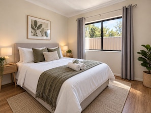 Quarto com cama, mesas de cabeceira, janela com cortinas, uma planta e um quadro na parede.