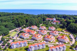 An aerial view of a residential area with multiple buildings, a large estate, and a view of the sea. - Holiday apartment Sonnentau Premium (Koserow)
