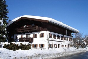 Ein zweistöckiges Chalet mit verschneitem Dach und Holzbalkonen.