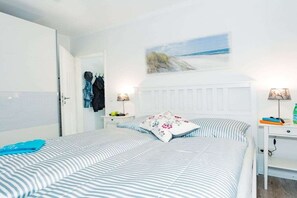 A bedroom with a bed, a nightstand, a lamp, and a painting on the wall. - Holiday apartment with 2 bedrooms (Scharbeutz)