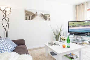 A living room with a sofa, coffee table, and a television. - Holiday apartment with 2 bedrooms (Scharbeutz)
