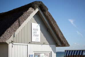 Un bâtiment doté d’un toit de chaume et d’une enseigne indiquant le numéro d’une pièce.