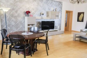 A dining area with a round table and chairs, a television, and a fireplace. - Holiday apartment with 1 bedroom (Ahlbeck)