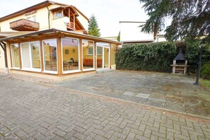 A house with a covered patio area, a chimney, and a hedge. - Holiday apartment with 1 bedroom (Ahlbeck)