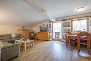 A cozy living room with a sofa, a wooden coffee table, a dining table with chairs, a wooden cabinet, and a television. - Country house - Praxmarer (Neustift im Stubaital)