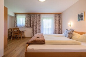 Habitación de hotel con dos camas, un escritorio de madera y una silla.