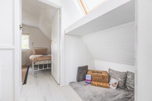 Une pièce avec un lit en mezzanine, un petit coin salon avec des coussins et une fenêtre donnant sur un beau paysage.