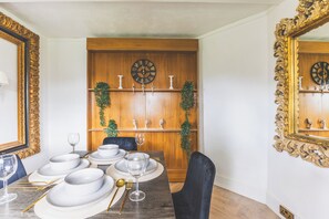 Ein Essbereich mit einer Holzwand, einer Uhr und einem Spiegel mit aufwendiger Rahmung.