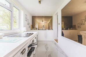 Eine Küche mit weißen Schränken, einer Glasrückwand und einem Marmorboden.
