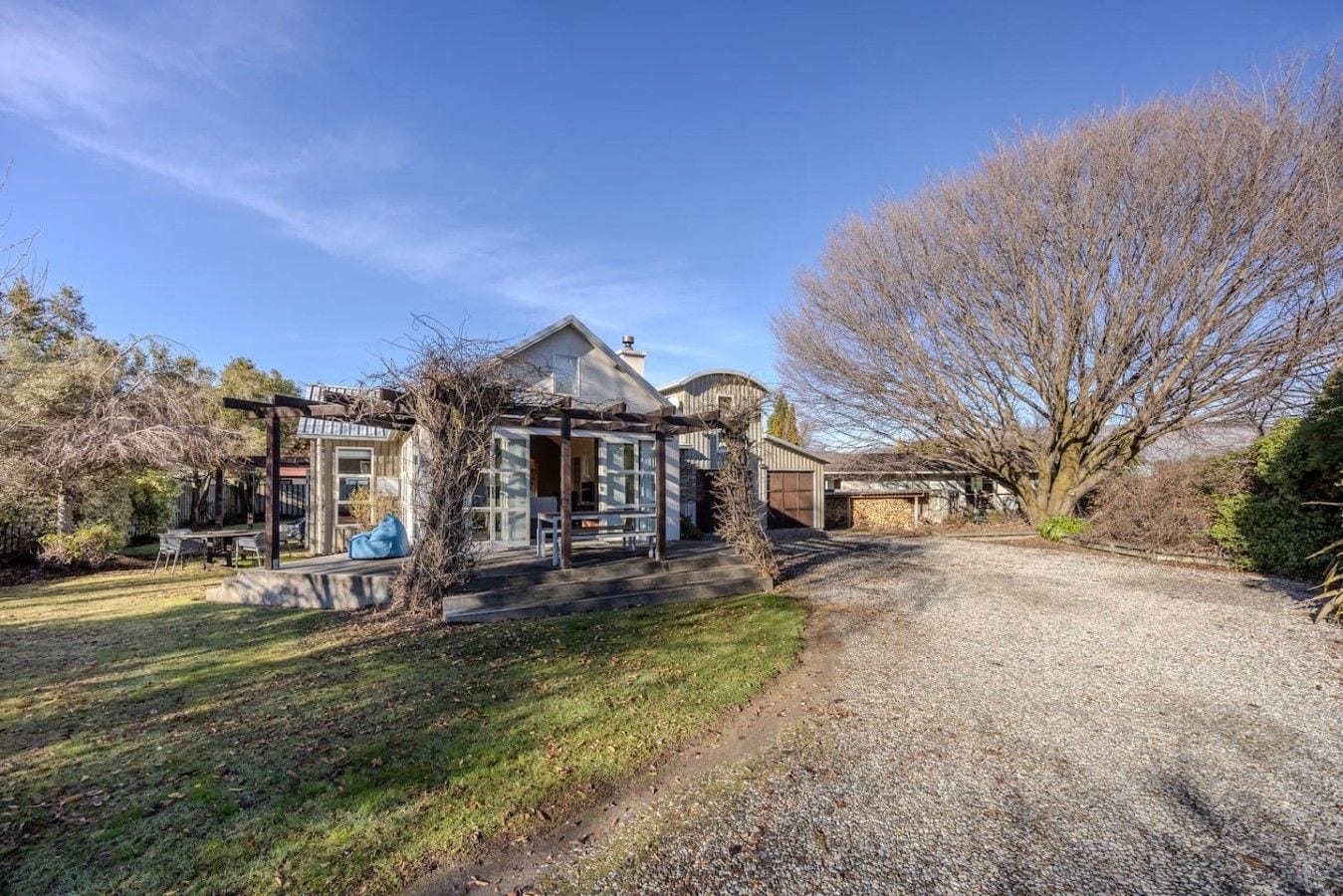 A two-story house with a covered patio, a garage, and a gravel driveway.
