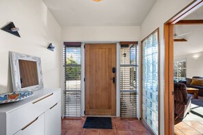 Ein Flur mit einer Holztür, einem weißen Schrank und einem gefliesten Boden.
