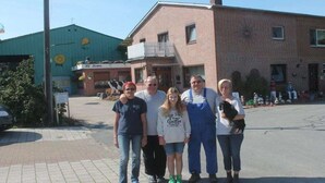 A group of people standing in front of a building with a brick facade and a balcony. - - Karstens Holiday Farm (Elpersbüttel)