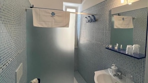 Une salle de bain équipée d’une douche, de toilettes, d’un lavabo et d’un porte-serviettes.