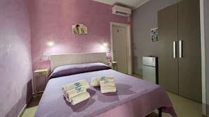 Une chambre à coucher comprenant un lit, des tables de chevet, un appareil de climatisation, une armoire et une porte.