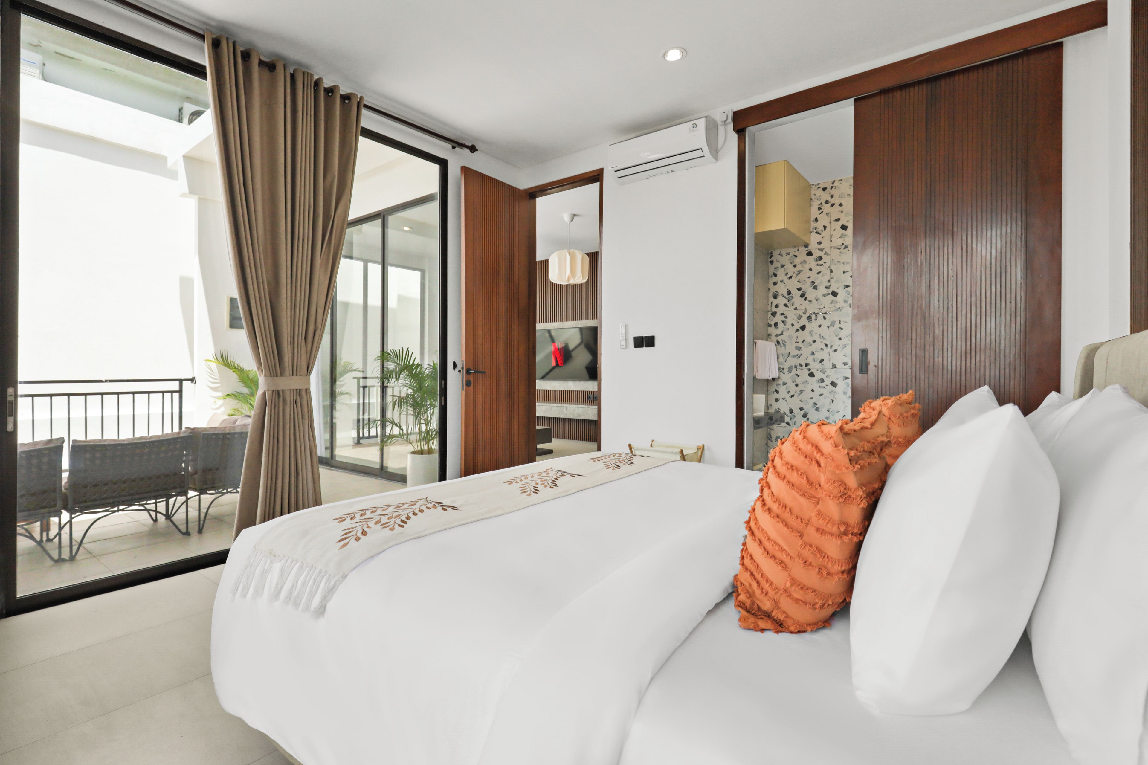 A hotel room with a bed, a balcony, and a view of the outdoors.