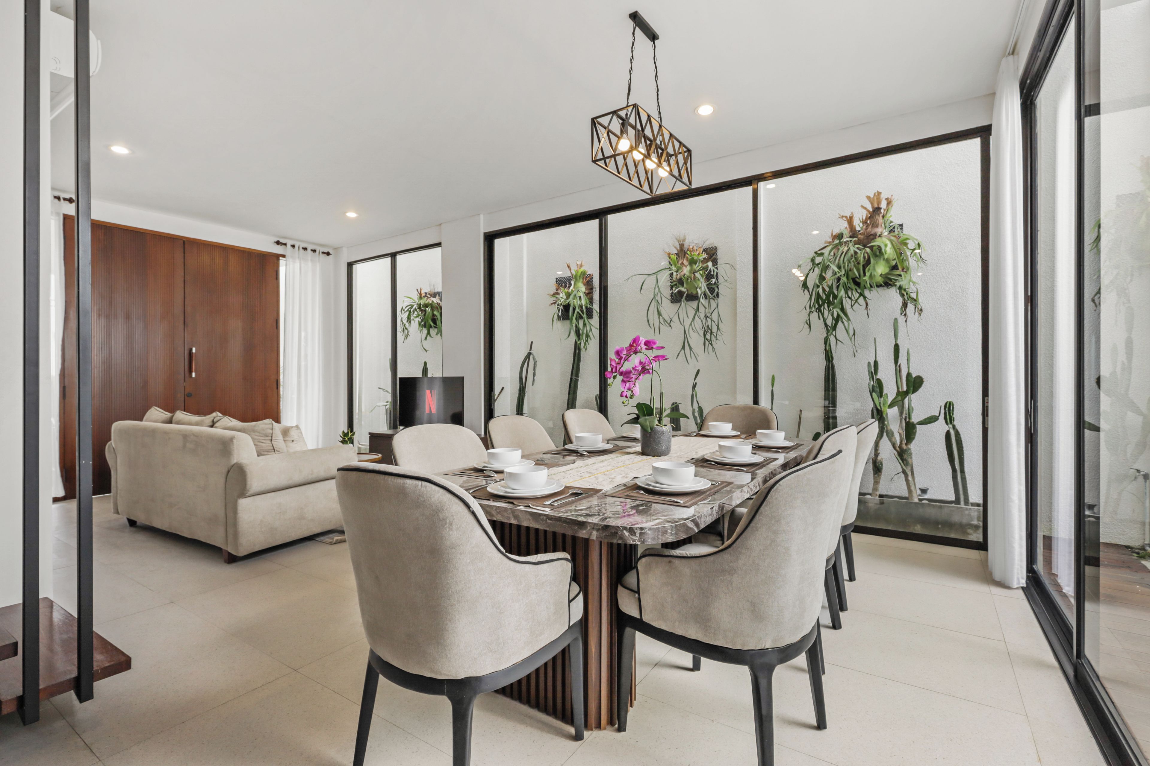 Un comedor moderno con una mesa grande dispuesta para seis personas, rodeada de sillas.