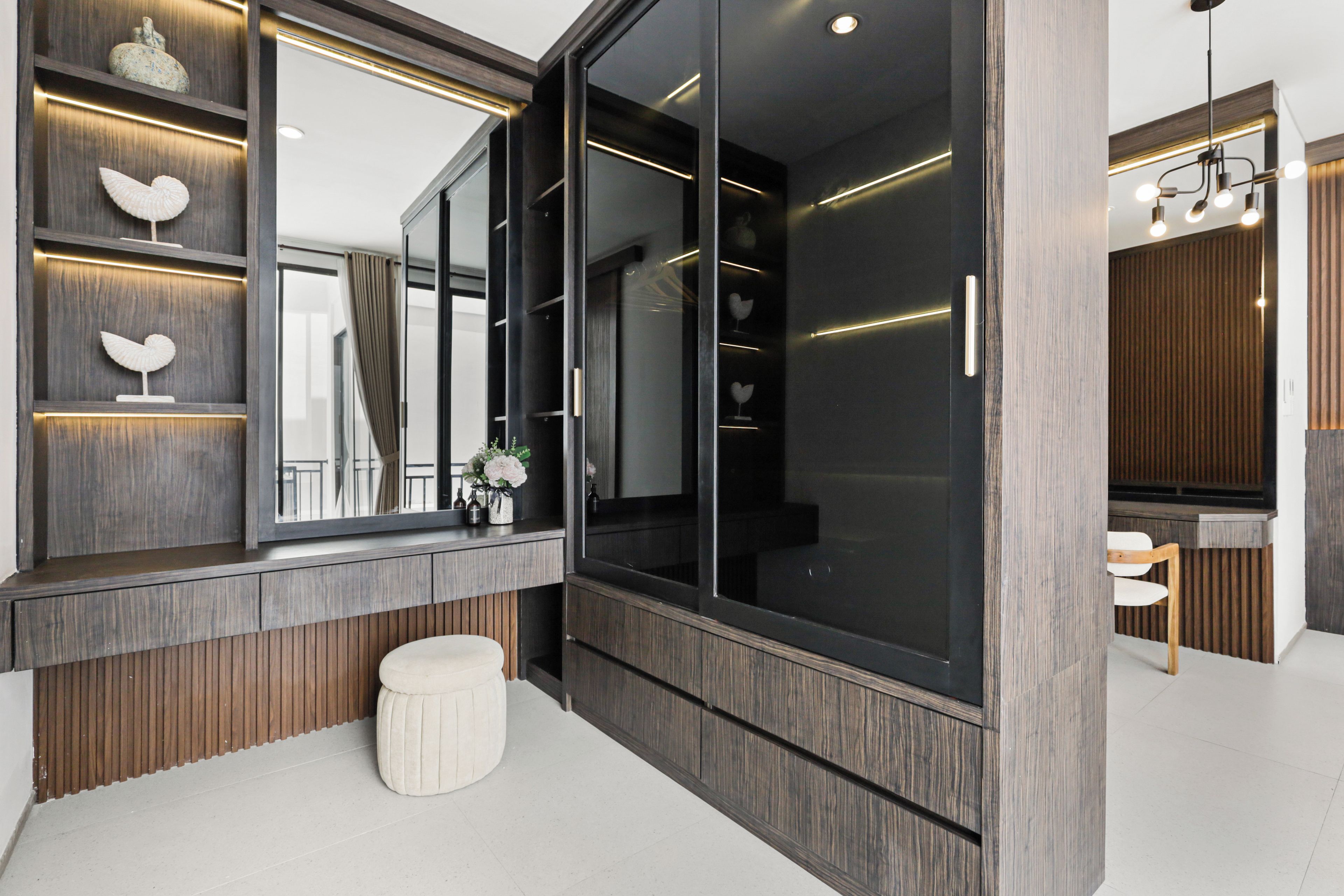 Un baño moderno con un espejo grande, paneles de madera y un banco blanco.