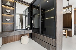 Un baño moderno con un espejo grande, paneles de madera y un banco blanco.