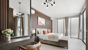 A modern hotel room with a large bed, a desk, a chair, a mirror, and a view of the outside. - Allena Villa by Kozystay - Canggu (Badung)