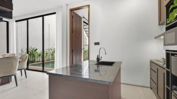Una cocina moderna con una isla central, un lavaplatos integrado y una zona de comedor con sillas.